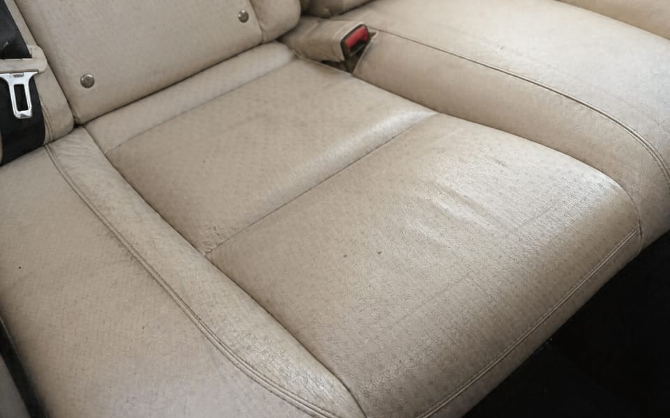 Asiento de cuero beige con grietas de suciedad y aspecto desgastado por falta de hidratación