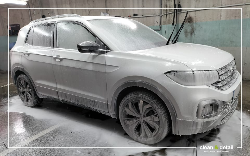 Coche SUV cubierto de espuma activa durante un proceso de lavado exterior premium