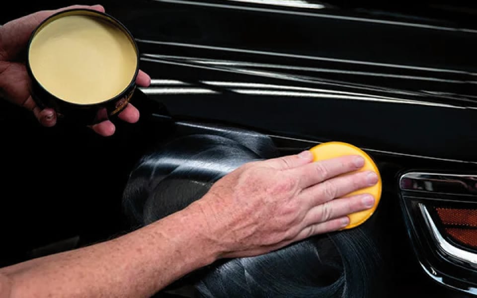 Detalle del proceso de aplicación uniforme de ceras protectoras en la carrocería de un coche