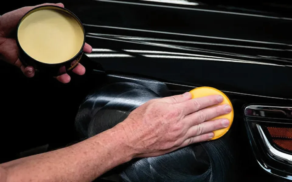 Detalle del proceso de aplicación uniforme de ceras protectoras en la carrocería de un coche